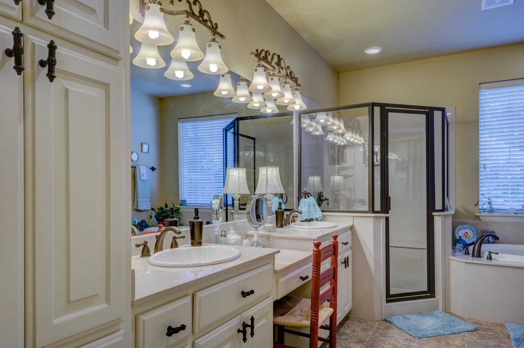 Cuarto de baño con lavabo doble, apliques de luz sobre el espejo, ducha de mampara y bañera